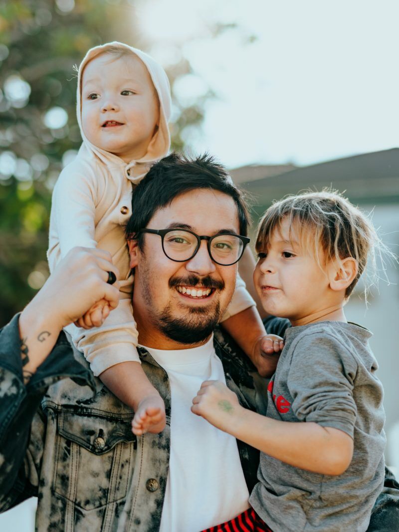 man in white shirt carrying girl in gray shirt