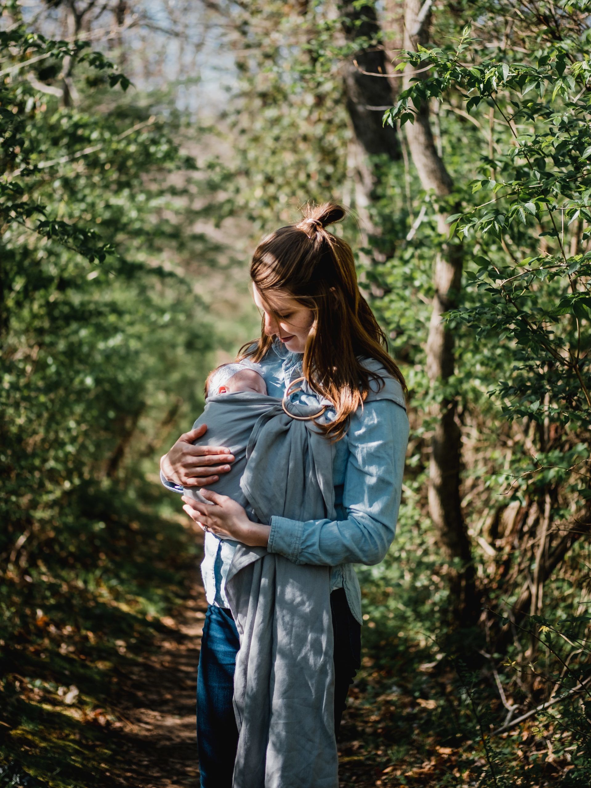 woman carrying child while standing near trees at daytime