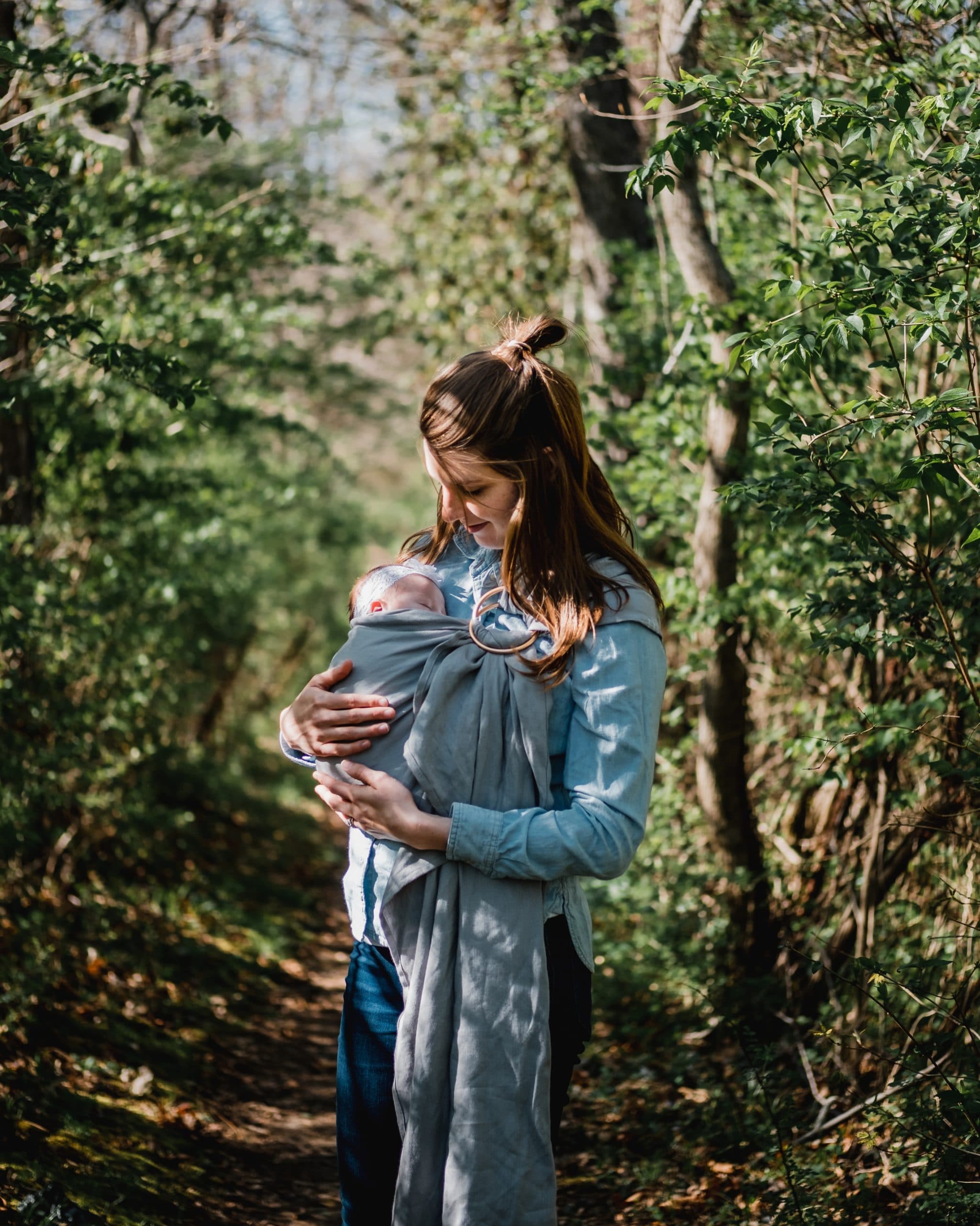 woman carrying child while standing near trees at daytime