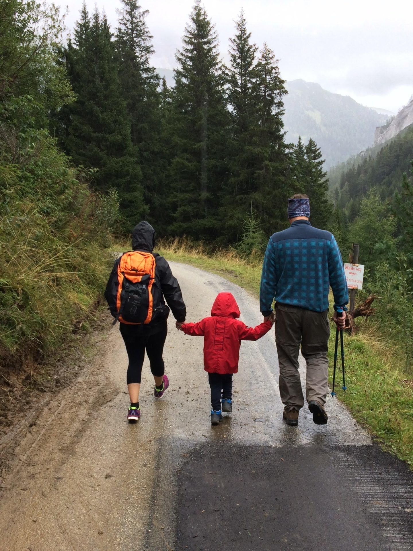 man, woman, and child walking together along dirt road