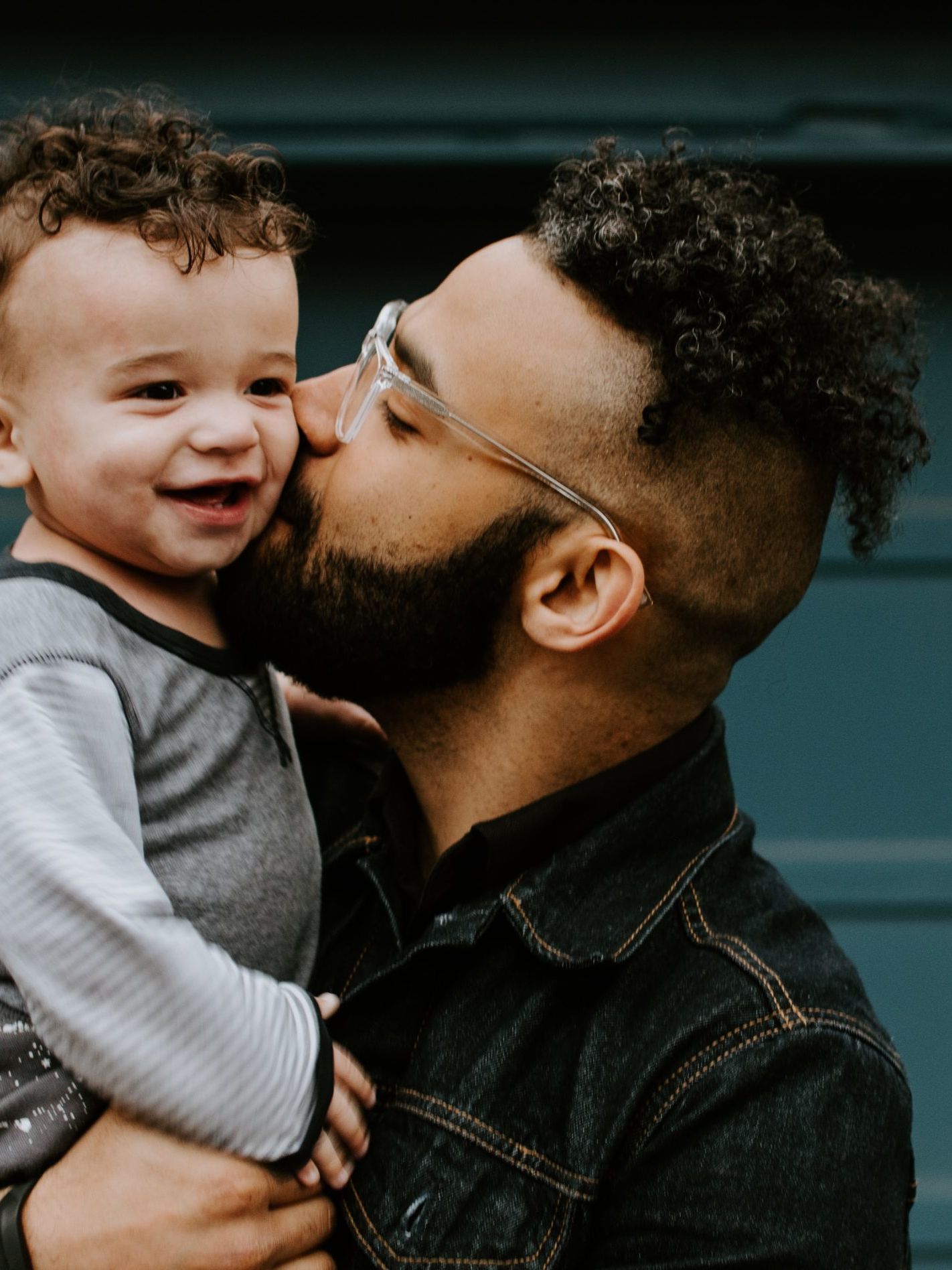 man carrying baby boy and kissing on cheek