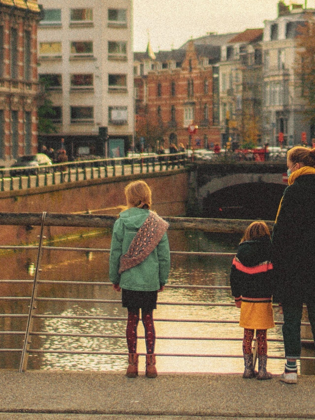 man in black jacket and blue denim jeans walking on bridge during daytime