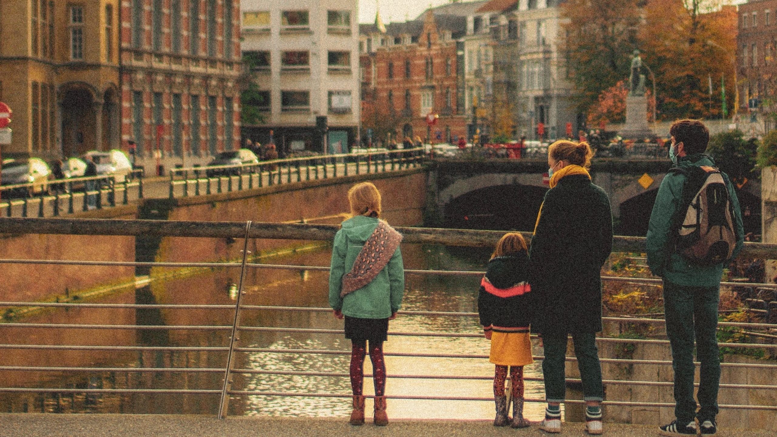 man in black jacket and blue denim jeans walking on bridge during daytime