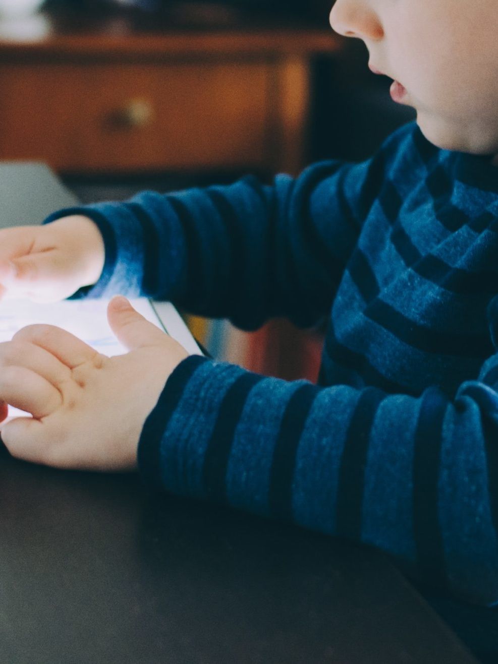 boy sitting on chair beside table using tablet computer