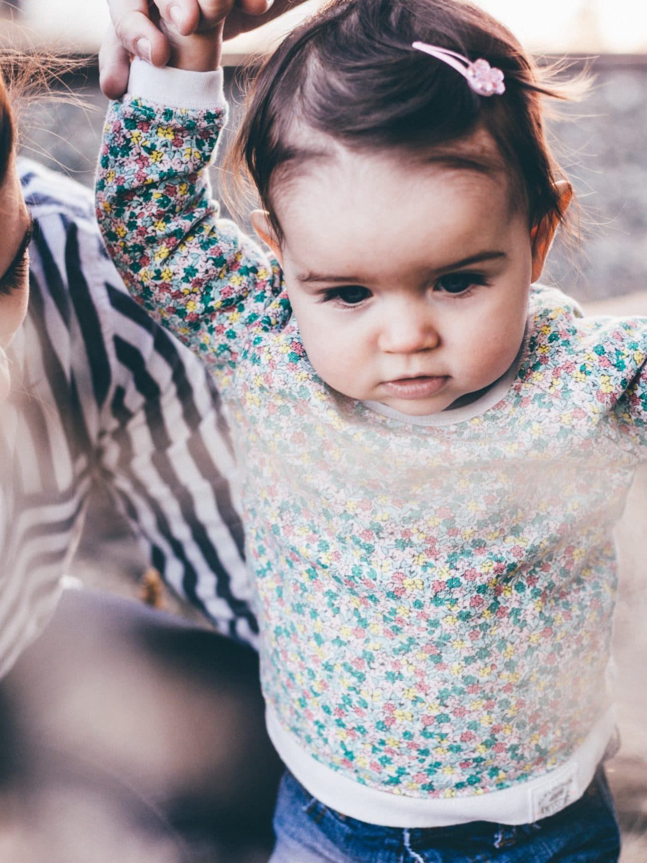 woman holding girl while learning to walk taken at daytime