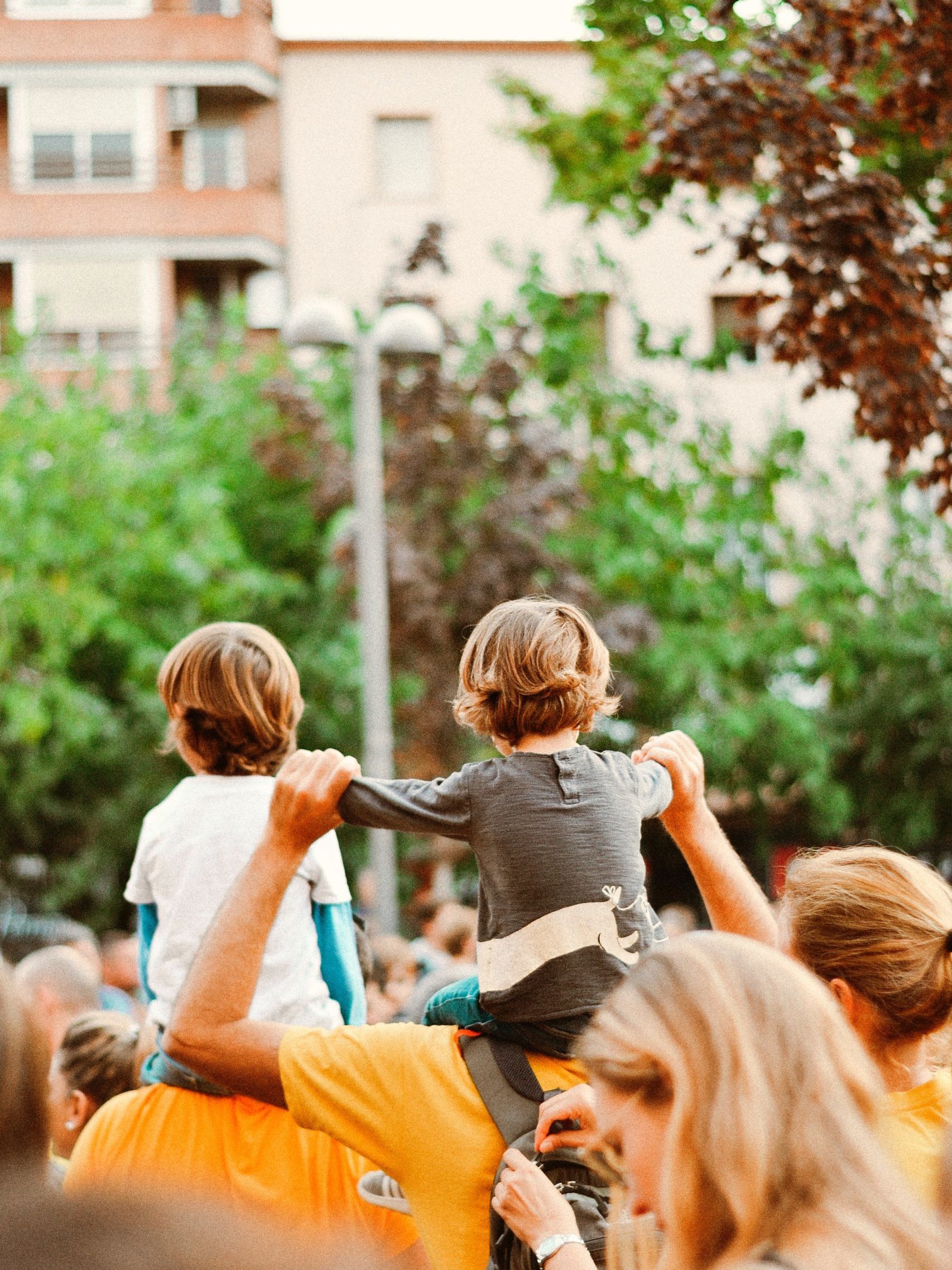 woman in gray t-shirt carrying child in blue and orange stripe t-shirt during daytime