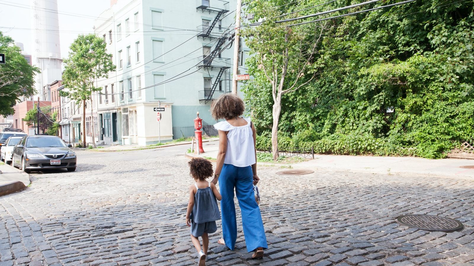 woman in white cap-sleeved shirt and blue pants walking beside girl in gray tank top