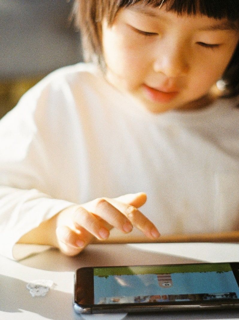 woman in white long sleeve shirt holding black smartphone