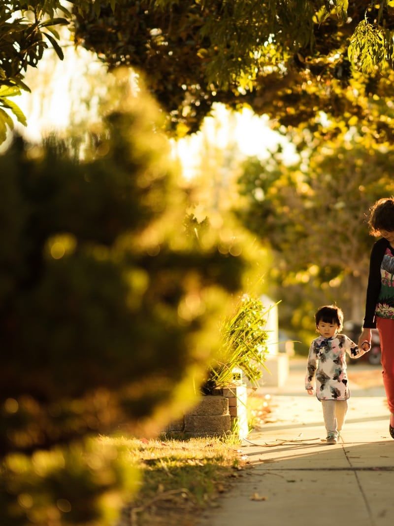 woman holding a child walking in the pathway