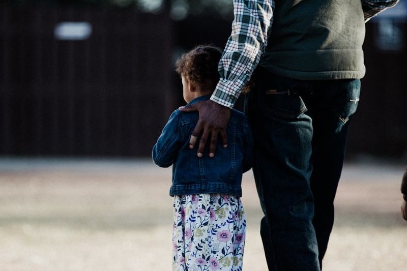 man in black and white checkered dress shirt holding girl in pink and white floral dress