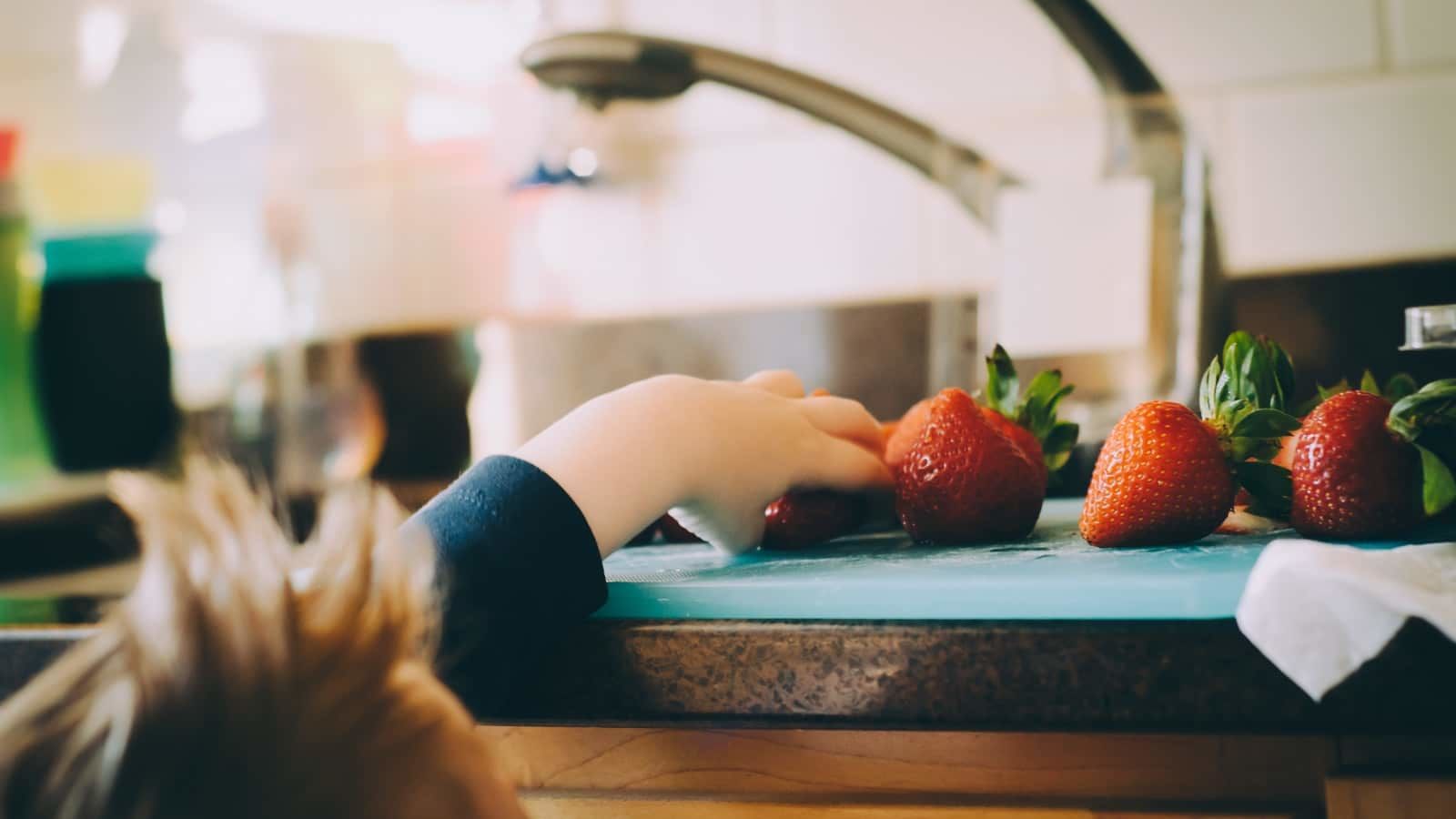 child picking strawberries in kitchen