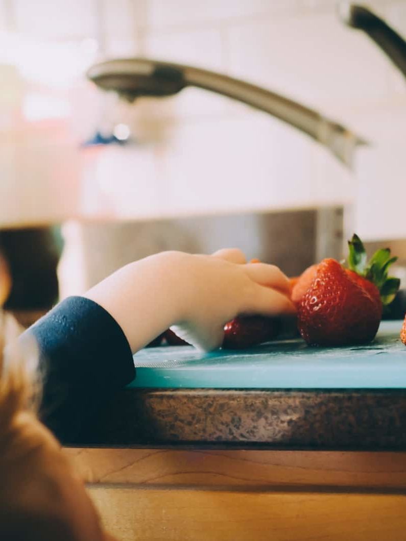 child picking strawberries in kitchen