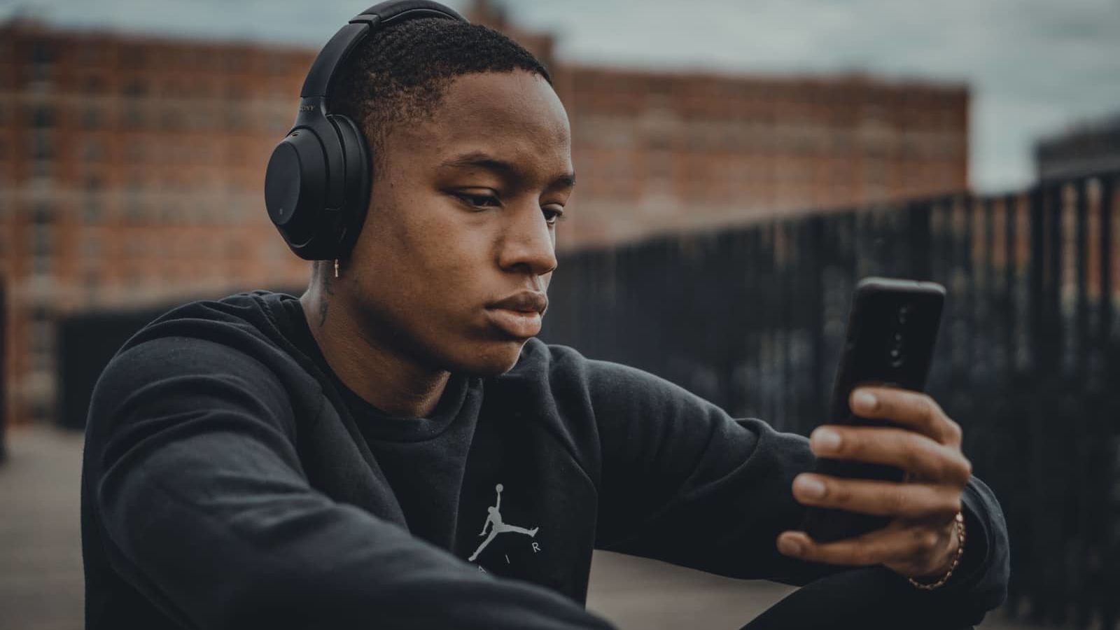 man in black nike hoodie wearing black headphones