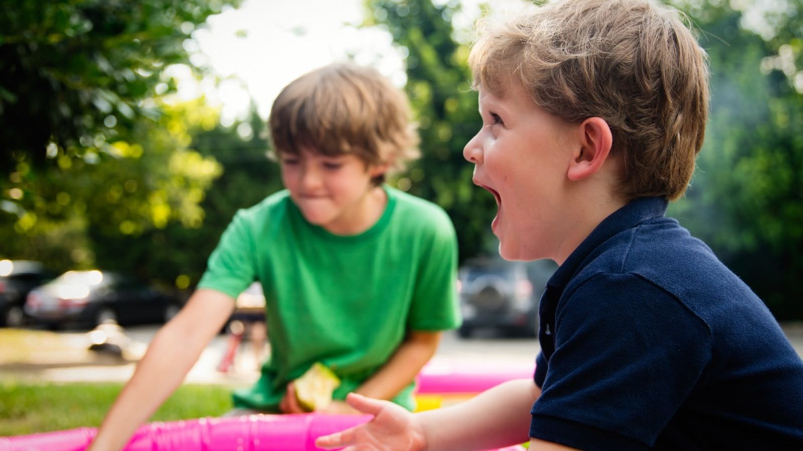 boy in blue shirt screaming near boy in green crew-neck shirt