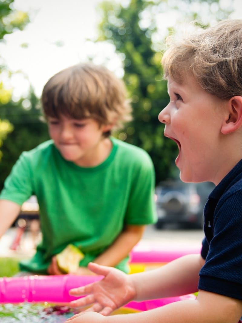 boy in blue shirt screaming near boy in green crew-neck shirt