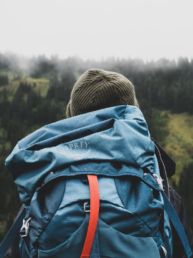 person wearing teal backpack looking at mountain