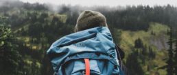 person wearing teal backpack looking at mountain