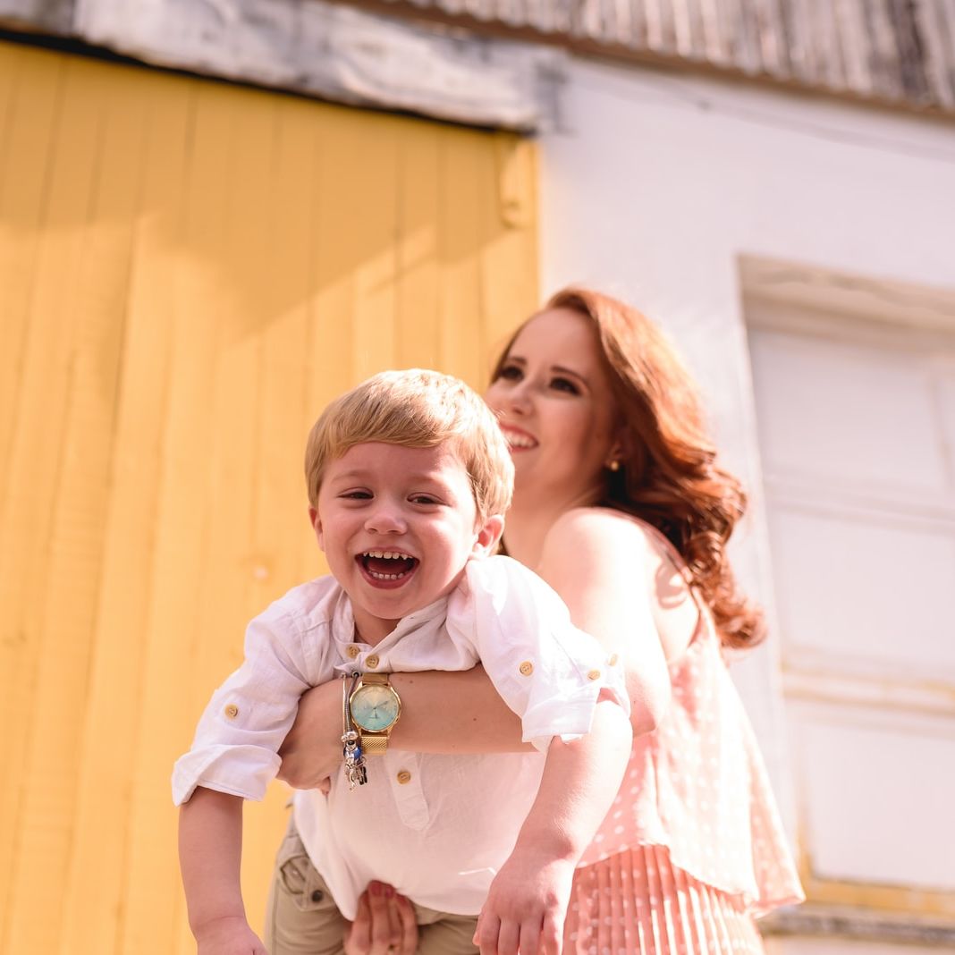 woman in blue and white plaid dress shirt carrying girl in white shirt