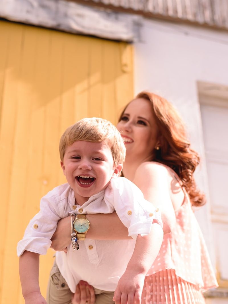 woman in blue and white plaid dress shirt carrying girl in white shirt