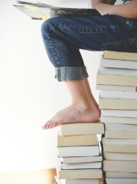 person sitting on stack of books while reading