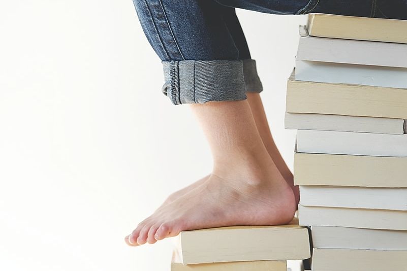 person sitting on stack of books while reading