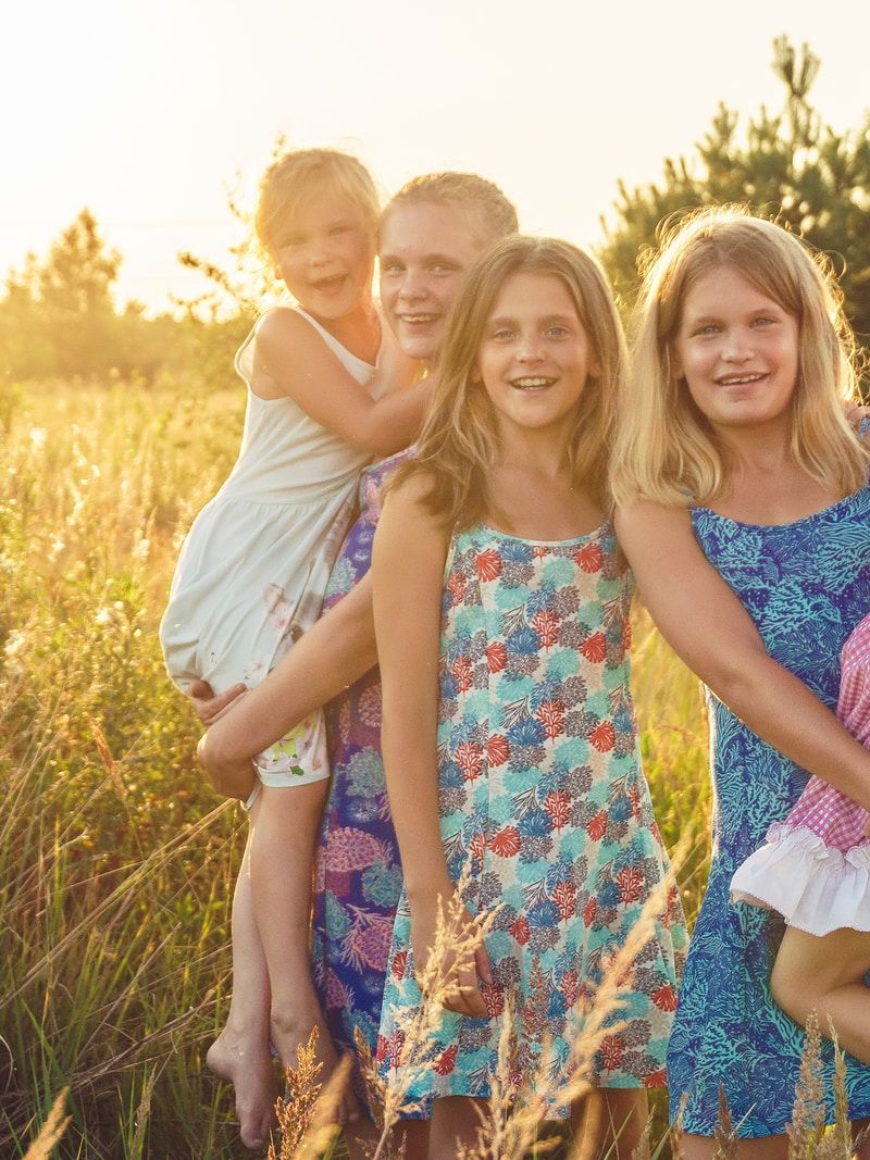 3 women and 2 girls standing on green grass field during daytime