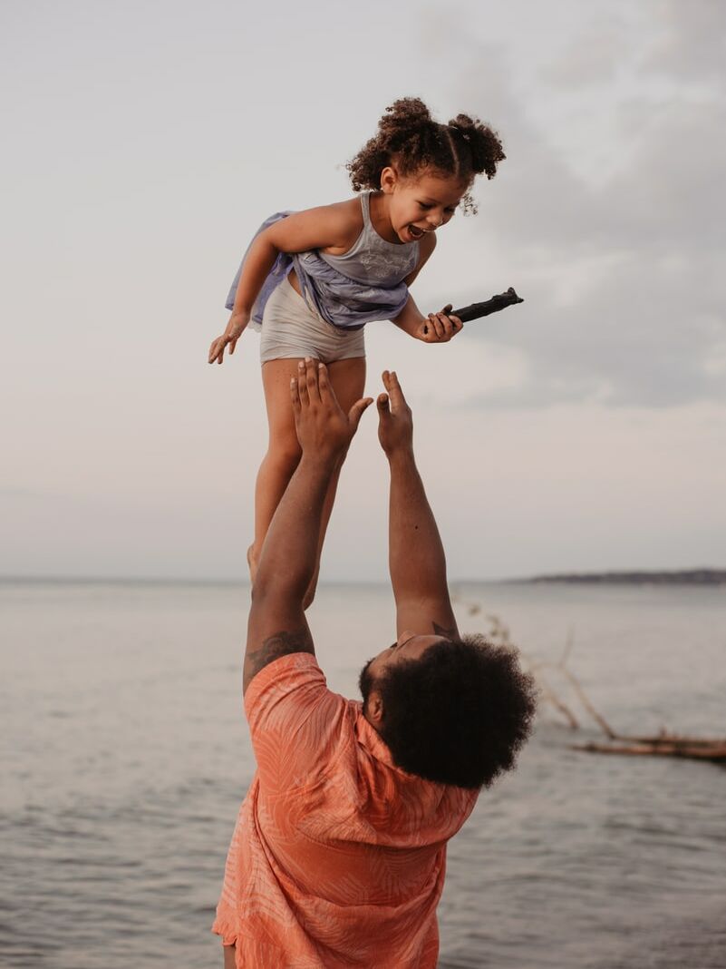 man in pink shirt lifting up girl