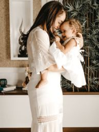 smiling woman in white dress holding toddler