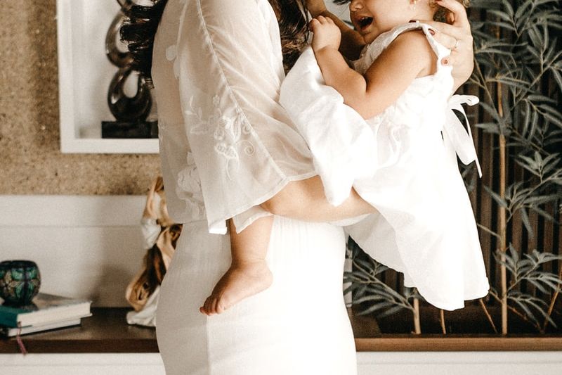 smiling woman in white dress holding toddler