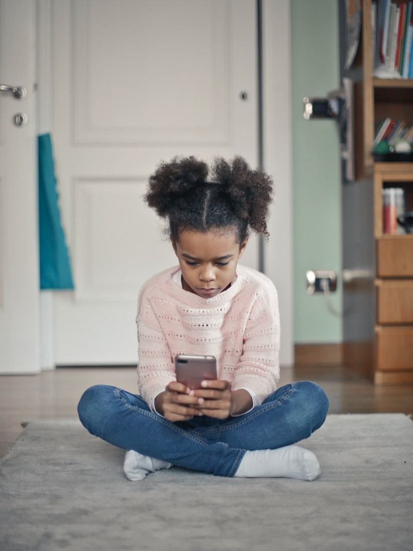 girl in white sweater and blue denim jeans sitting on floor