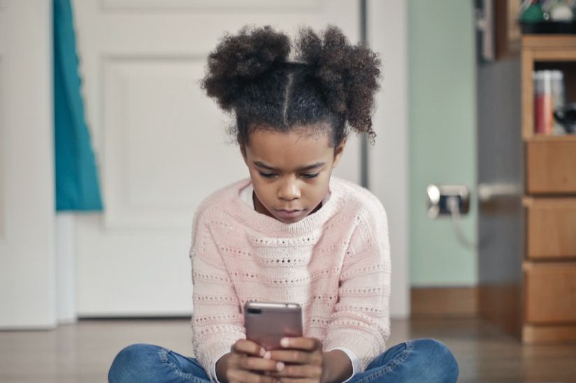 girl in white sweater and blue denim jeans sitting on floor