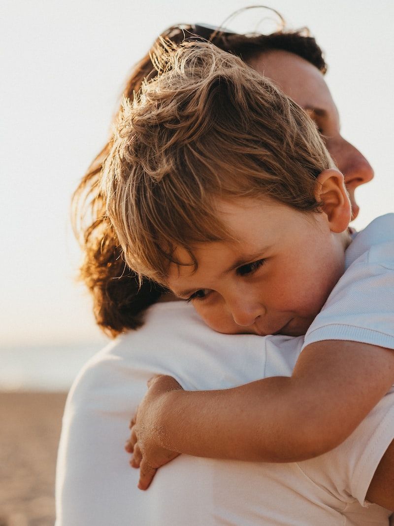 boy hugging woman during daytime