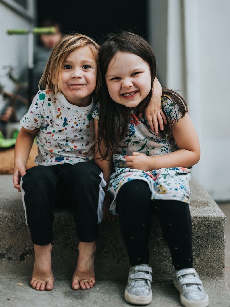 2 girls sitting on concrete floor