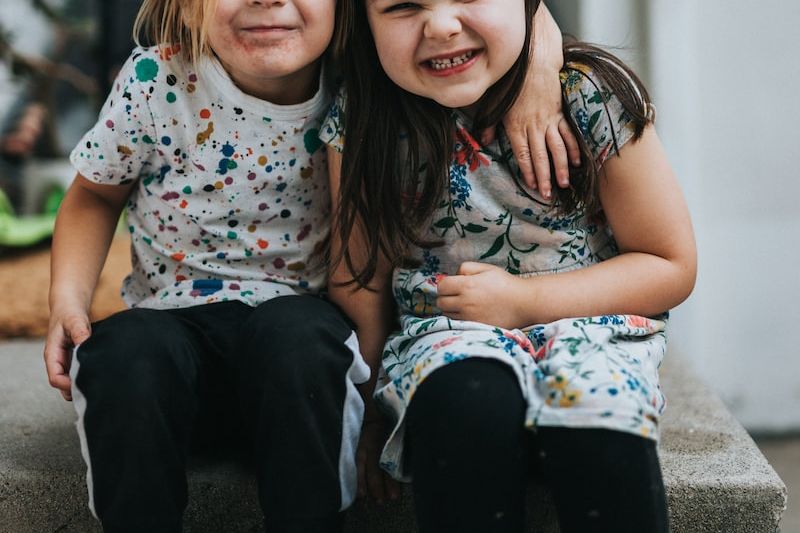 2 girls sitting on concrete floor