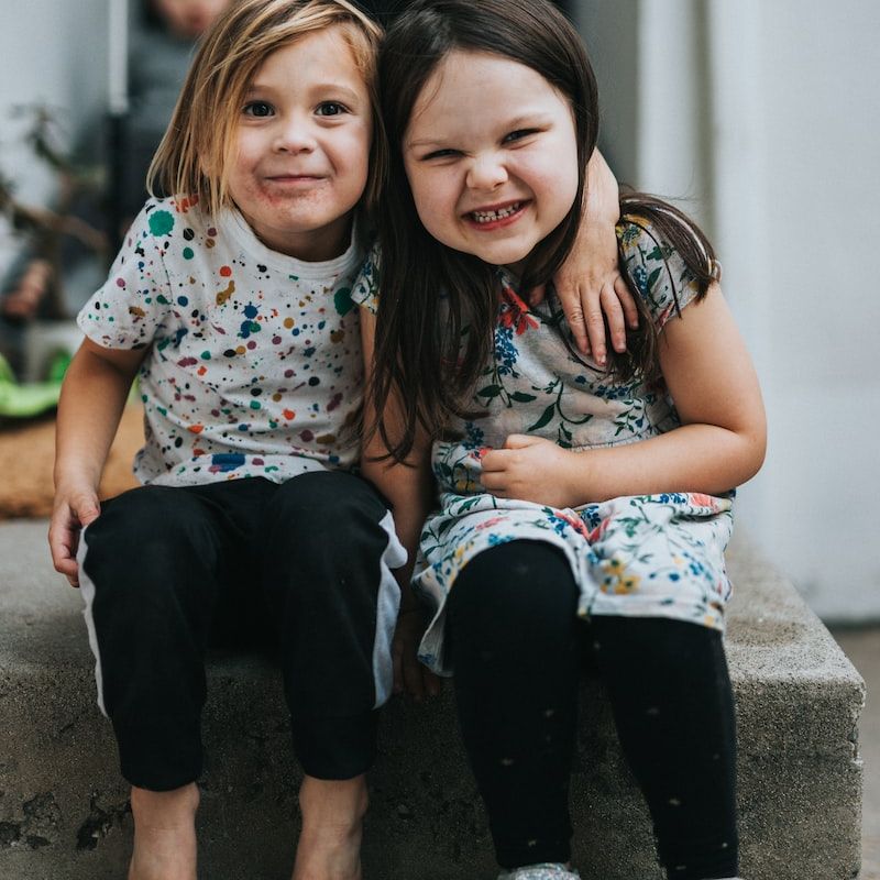 2 girls sitting on concrete floor