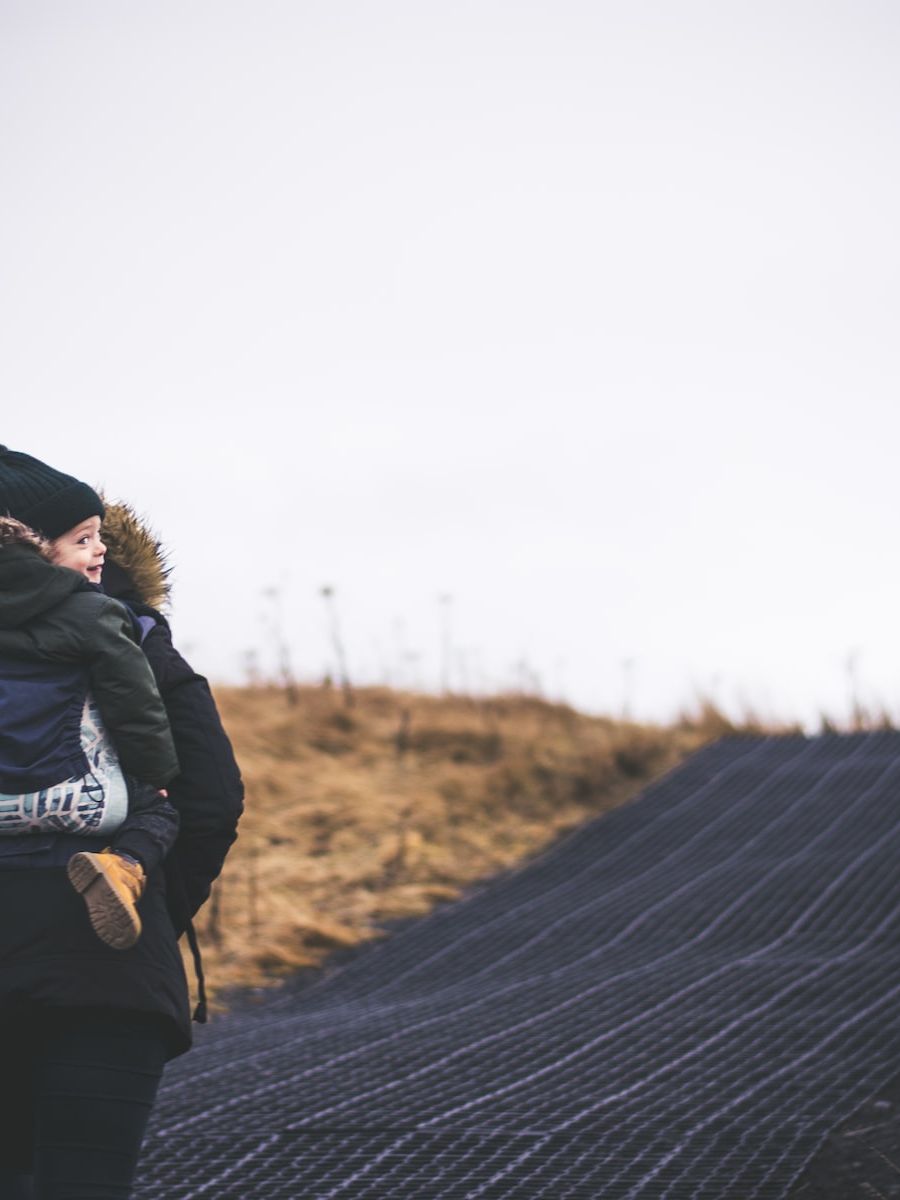 woman carries child piggy back on blacktop road