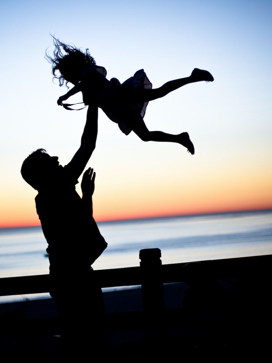 silhouette of man throwing girl in air