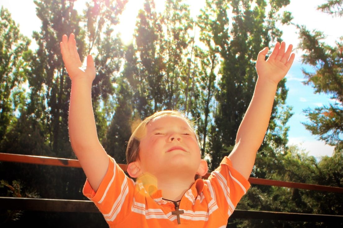 girl in orange and white striped polo shirt standing on wooden fence during daytime