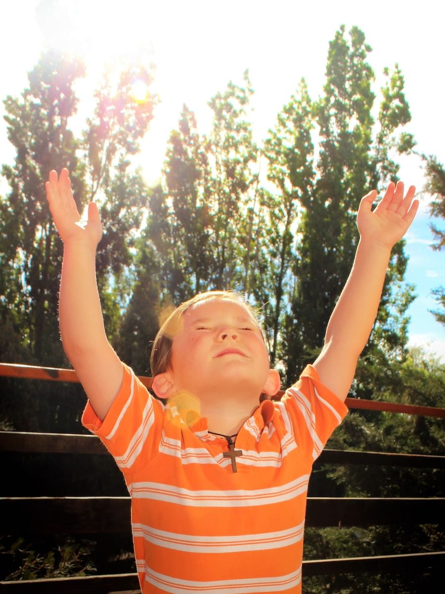 girl in orange and white striped polo shirt standing on wooden fence during daytime