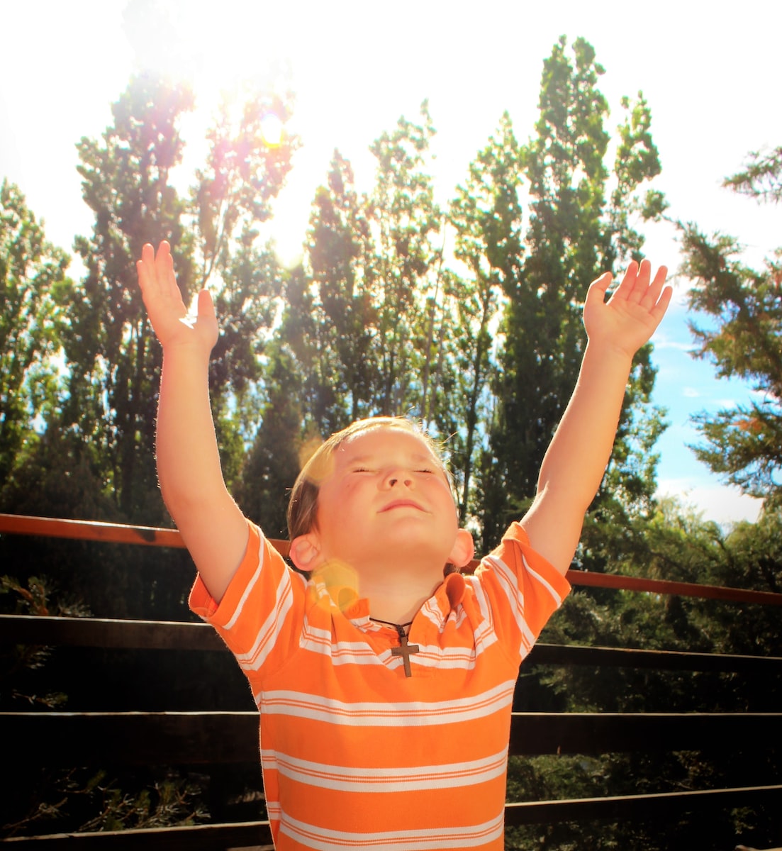 girl in orange and white striped polo shirt standing on wooden fence during daytime