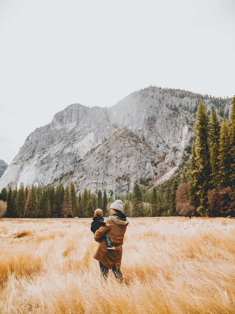 person standing on grass field while carrying child