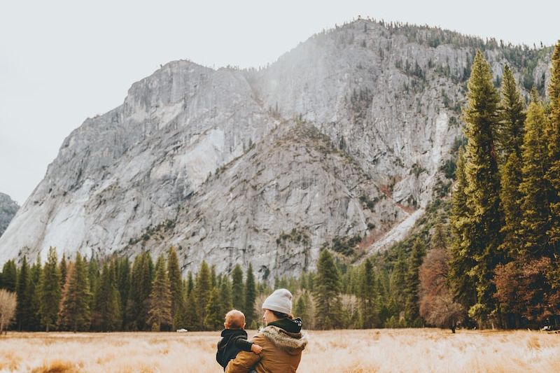 person standing on grass field while carrying child