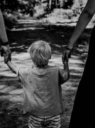 grayscale photo of woman in black dress holding child in black shirt