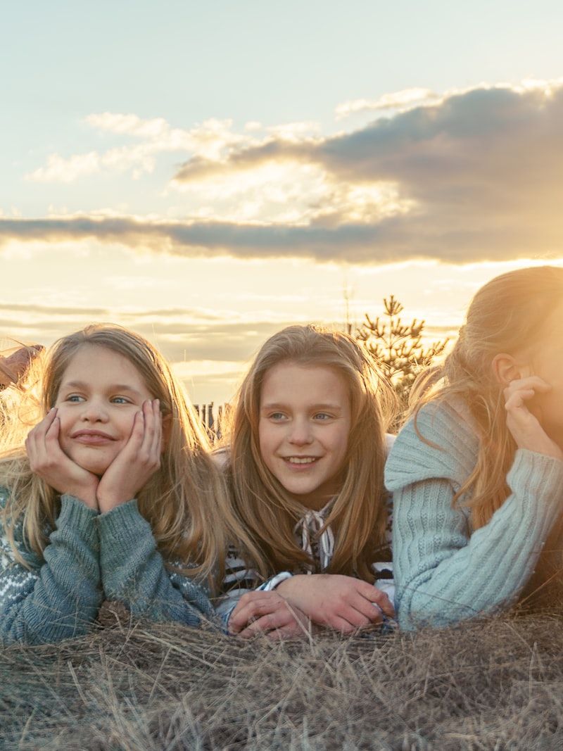 3 women sitting on grass field during sunset