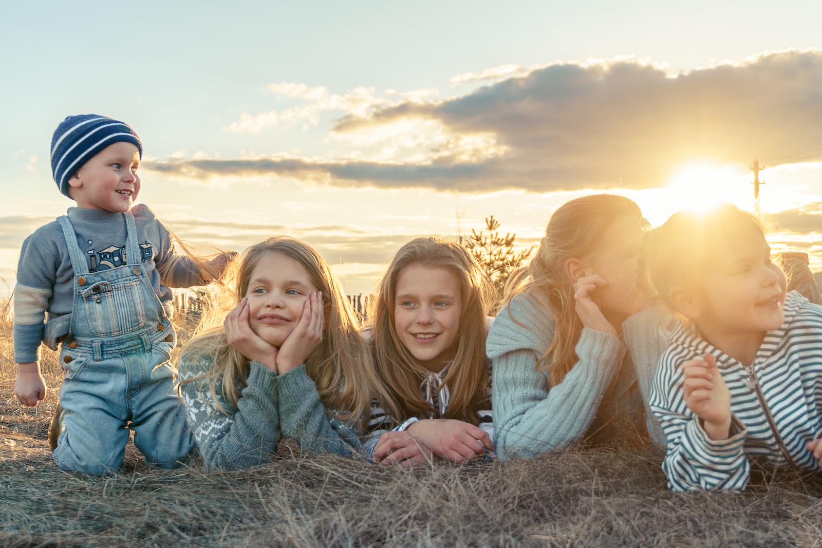 3 women sitting on grass field during sunset