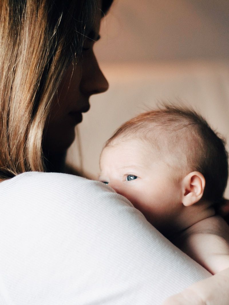 woman in white shirt carrying baby