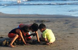 three children playing in the sand at the beach