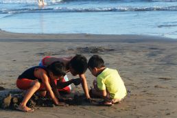 three children playing in the sand at the beach
