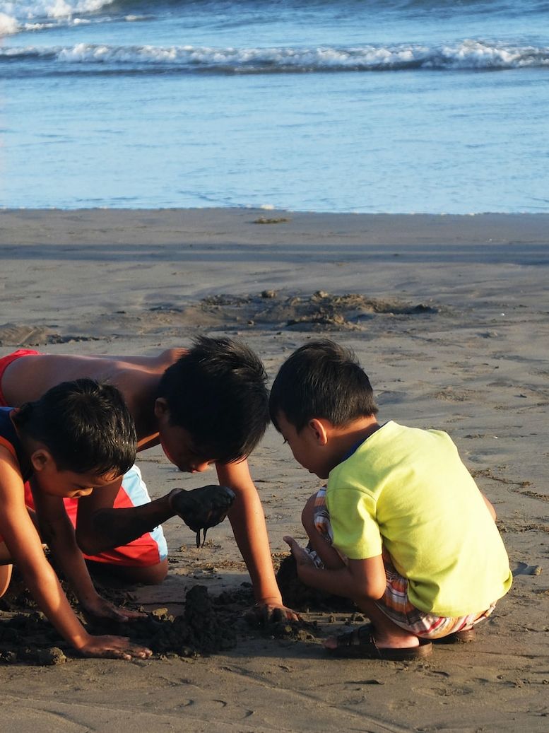 three children playing in the sand at the beach