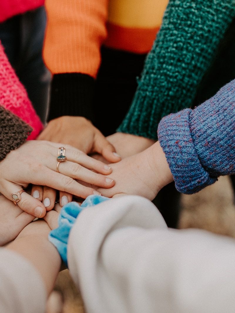 person in red sweater holding babys hand